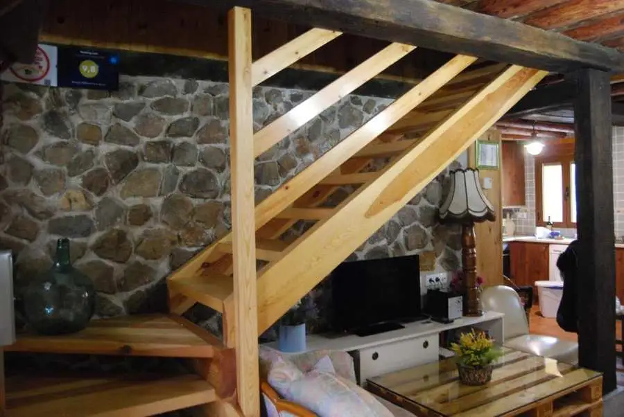 Salón rústico con escalera de madera en alojamiento rural